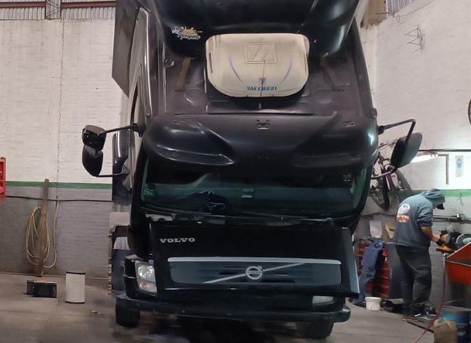 Camión Volvo dentro del taller, con un mecánico trabajando al fondo